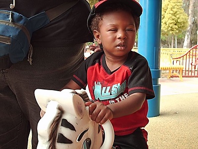 A blind child playing on a rocking horse